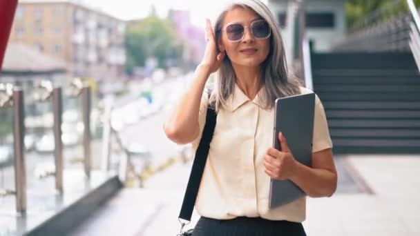 La mujer asiática de mediana edad está ordenando su cabello y tocando sus gafas de sol — Vídeo de stock