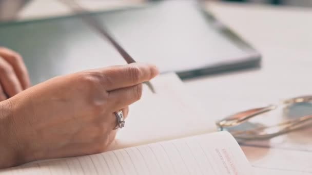 Женская рука пишет в блокноте — стоковое видео