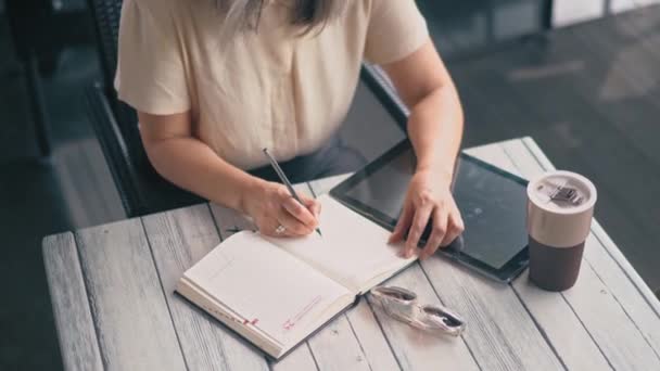 La mujer está escribiendo en su cuaderno — Vídeo de stock