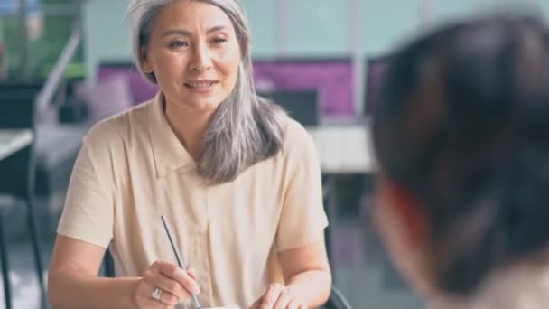 Dos mujeres están sentadas y hablando en la oficina — Vídeos de Stock