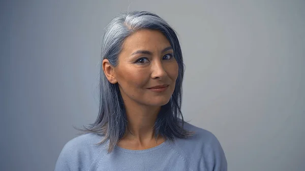 Niedliche asiatische Frau mittleren Alters auf dem grauen Hintergrund — Stockfoto