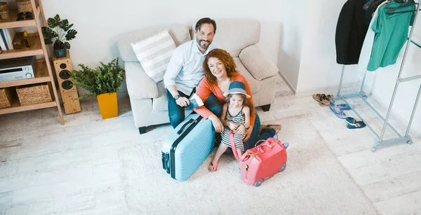 Ευτυχισμένη οικογένεια πηγαίνει διακοπές, κάθεται στον καναπέ με βαλίτσες. — Φωτογραφία Αρχείου