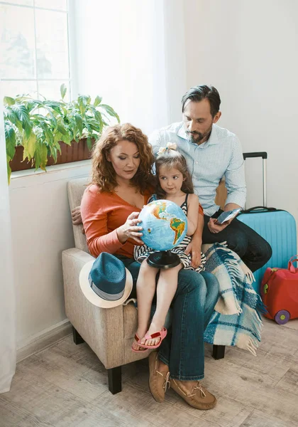 Felice famiglia seduta in poltrona studiando globo . — Foto Stock