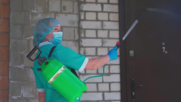 살균제가 있는 공공 지역의 감염. 제복을 입은 한 여자는 돌아서서 진료소 입구를 소독하면서 카메라를 쳐다보았다. 시립 병원. 2020 년 5 월, 우크라이나 브로바리 — 비디오
