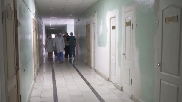 Médicos em movimento caminham pelo corredor do hospital. Equipe de trabalhadores médicos em uniformes coloridos andando ao longo do salão. Imagem embaçada abstrata. Hospital da cidade. Maio, 2020, Brovary, Ucrânia — Vídeo de Stock