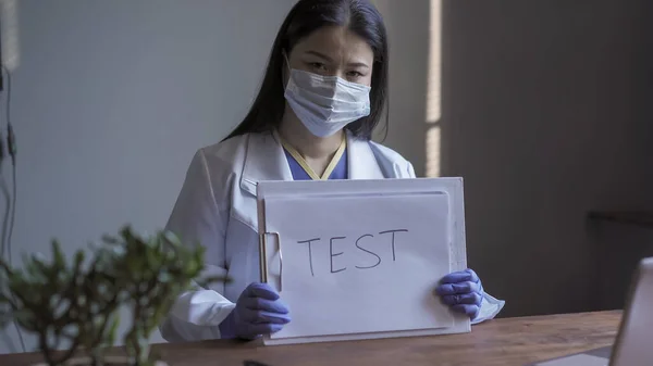 Médico oferecendo-se para fazer o teste médico para o diagnóstico da doença. Mulher asiática vestindo uniforme de proteção olha para câmera segurando tablet com o teste de inscrição. Conceito de saúde — Fotografia de Stock