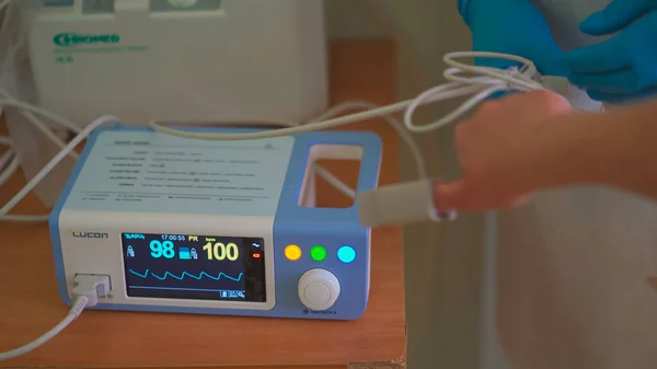 Pulsoximeter på jobbet. Medicinsk diagnosutrustning. Patienter hand med fäst pulsoximeter sensorelement i suddig förgrund. Stadssjukhuset. Maj 2020, Brovary, Ukraina — Stockfoto