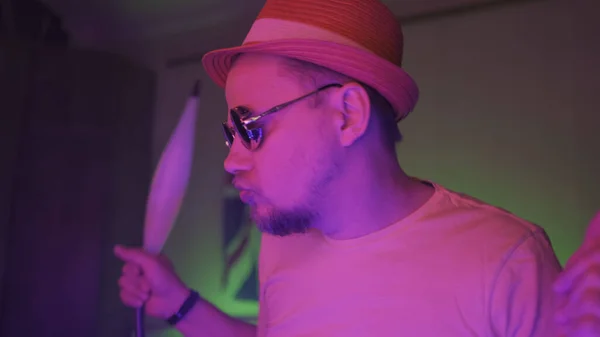 Hipster człowiek dansing podczas palenia hookah w różowym oświetleniu kolorów w domu ciemny pokój z neonów. Człowiek w ruchu, abstrakcyjny niewyraźny obraz — Zdjęcie stockowe