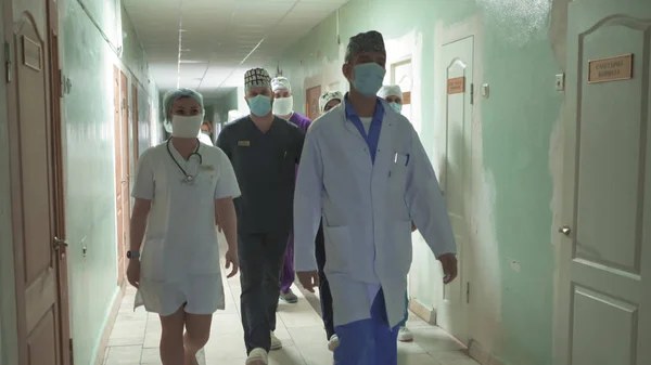 Лікарі в русі ходять по лікарняному коридору. По коридору ходить група лікарів у барвистих формах. Абстрактне розмите зображення. Міська лікарня. Травень 2020, Броварі, Україна — стокове фото