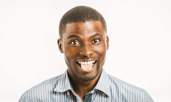 Vicces afro-amerikai férfi fogas mosoly mutatja nyelv közben kamerába. Fiatal férfi vállalkozó ing elszigetelt fehér háttér. Fej vállak portré. Érzelmek koncepciója. Tonozott kép — Stock Fotó
