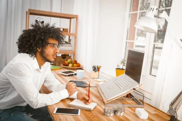 Mladý muž si dělá poznámky při plánování své práce. Student nebo podnikatel pracující z domova. Izolovaný obrázek — Stock fotografie