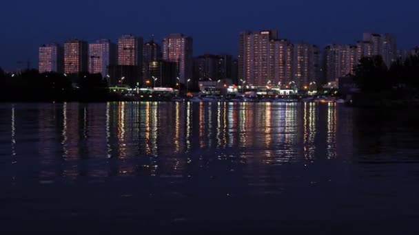 Egy pillantás az éjszakai vízre egy úszó hajóról. Egy modern város lakóépületekkel. 2019. augusztus. Kijev, Ukrajna. Gyümölcsfélék — Stock videók