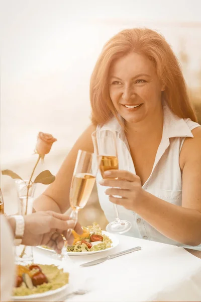 Lycklig kvinna dricker vitt vin med sin älskade man. Mogna par klamrar sig fast vid vinglas medan de sitter på ett sommarcafé utomhus. Lycklig tillsammans koncept. Tonad bild — Stockfoto