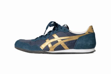 Blue sneakers of Asics brand. Stylish lace-up shoes for warm weather and a fitness hall. Blue suede shoes with gold accents cut out on white. Side view. May, 2019. Kiev, Ukraine clipart