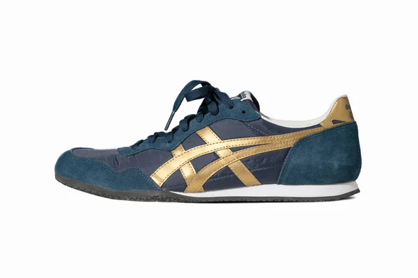 Blue sneakers of Asics brand. Stylish lace-up shoes for warm weather and a fitness hall. Blue suede shoes with gold accents cut out on white. Side view. May, 2019. Kiev, Ukraine — Stock Photo, Image