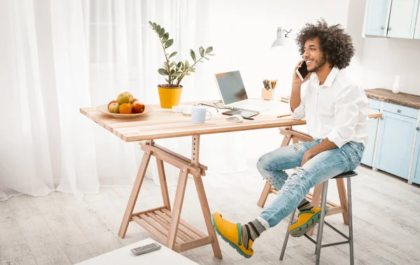 Uomo creativo parla sul cellulare che lavora da casa. Giovane ragazzo arabo in lavori casuali in studio casa cucina interna. Immagine tonica — Foto Stock