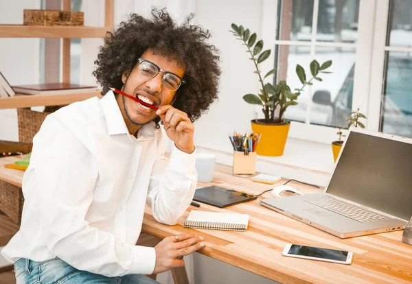 Autor emocional mordisquea un lápiz tratando de generar ideas para un nuevo artículo. Shaggy joven árabe que trabaja en un nuevo proyecto. Imagen tonificada — Foto de Stock