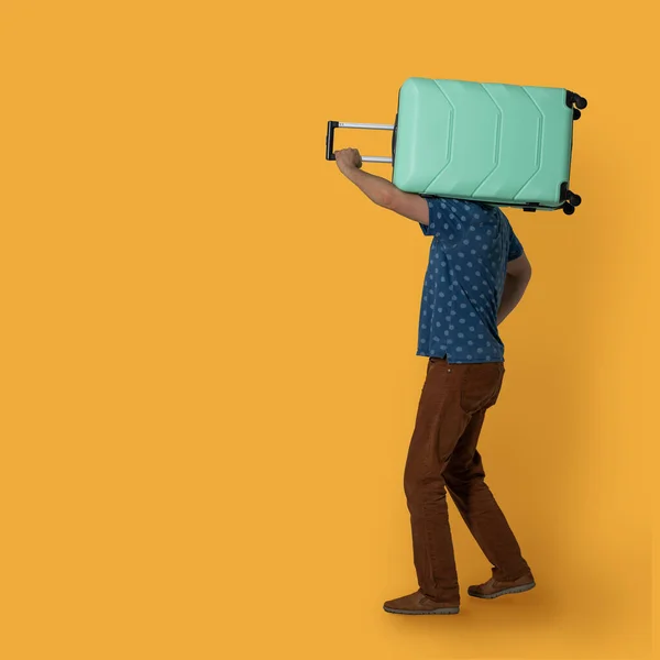 Han har en resväska på axeln. Sidovy av kaukasisk man som håller plast grön resväska med hjul och teleskopisk handtag när du åker på semester. Isolerad på färgad bakgrund. Resebegrepp — Stockfoto