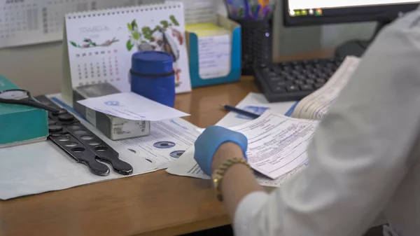 Le docteur travaille dans un cabinet d'ophtalmologiste. Médecin écrit des formulaires médicaux. Image déconcentrée abstraite. Concentre-toi sur le côté gauche. Hôpital municipal. mai 2020, Brovary, Ukraine — Photo