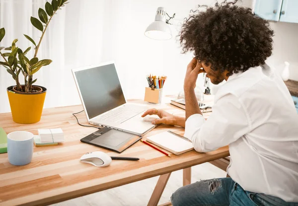 Stanco freelance uomo duro lavoro con computer portatile. Vista laterale di giovane studente o uomo d'affari seduto al tavolo di legno in interni di casa. Concetto di scadenza. Immagine tonica — Foto Stock