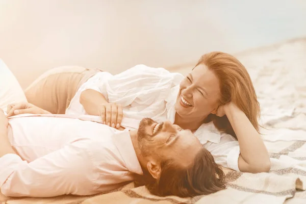 Laughing couple enjoying vacation on a sandy beach. Caucasian man and woman are happy spending time together. Mature people dating at coast. Toned image — Stock Photo, Image