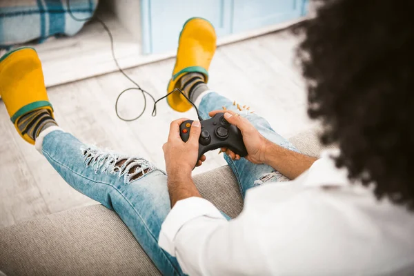 Gamer a jogar jogos de vídeo. Foco seletivo em mãos masculinas mãos pressionando botões no joystick para estação de jogo sentado no sofá. Vista de ângulo alto. Um tiro de perto. Imagem tonificada — Fotografia de Stock