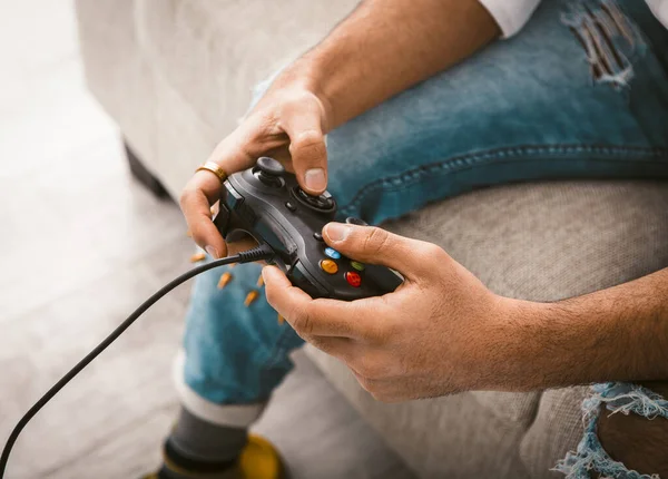 Beauty male hands using joystick. Gamer uses wired gamepad playing computer games. Close up shot. Home entertainment concept. Toned image — Stock Photo, Image