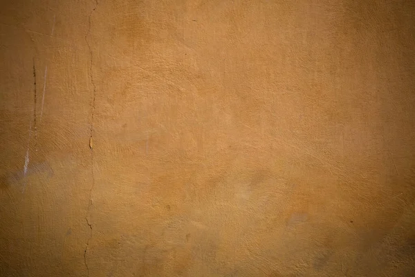 Ściana tynkowana grunge z pęknięciami. Tekstura, abstrakcyjne tło kolorowego stiuku pomarańczowego lub żółtego — Zdjęcie stockowe