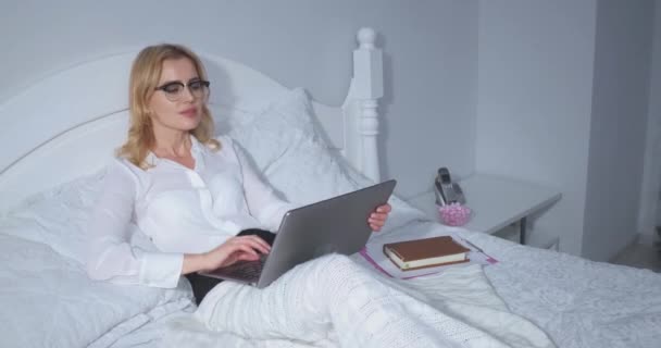 Bizneswoman w łóżku z laptopem patrząc dokumenty przez całą noc po długim ciężkim dniu. Bizneswoman relaksuje się w łóżku po długim locie. Koncepcja biznesu. Prores 422 — Wideo stockowe