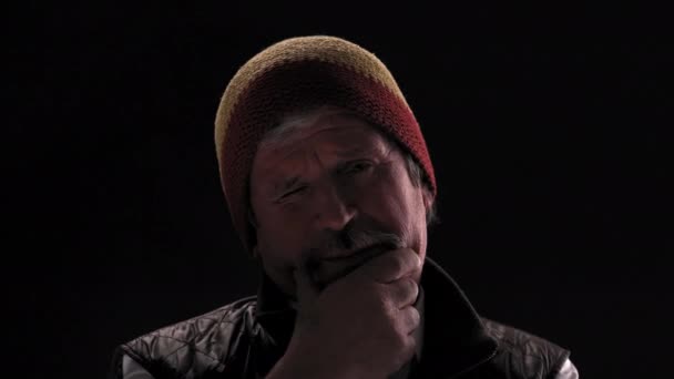 라스타 란 모자를 쓴 마약 중독자는 검은 배경에 고립되어 있는 반 조명 방에서 카메라 를 주의 깊이 응시하고 있는 턱을 만지작거리고 있다. 프로방스 422 — 비디오