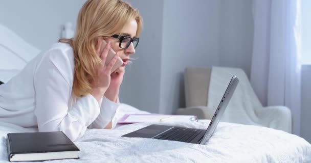 Freelance mulher ter um telefonema tarde da noite de um homem amado enquanto trabalhava em laptop deitado na cama. Mulher de negócios relaxa enquanto trabalha na cama. Conceito de negócio. Tintura fria. Prores 422 — Vídeo de Stock