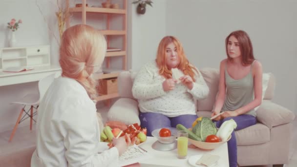 Βουλιμική και υπέρβαρη κοπέλα που δοκιμάζει ψωμάκια. Γιατρός μιλάει για το πρόβλημα βάρους και συμβουλεύει για θέματα υγείας με τα κορίτσια φίλους της. Υγιεινή διατροφή. Βαμμένο βίντεο. Πρότυπα 422. — Αρχείο Βίντεο