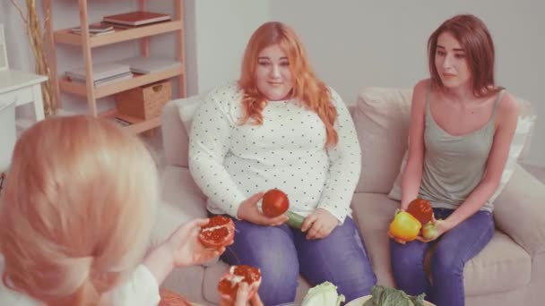 Two girl. Bulimic and overweight girl trying fresh fruits and vegetables. Doctor talking about weight problem and consults about health issues. Healthy food concept. Tinted video. Prores 422 — Stock Video