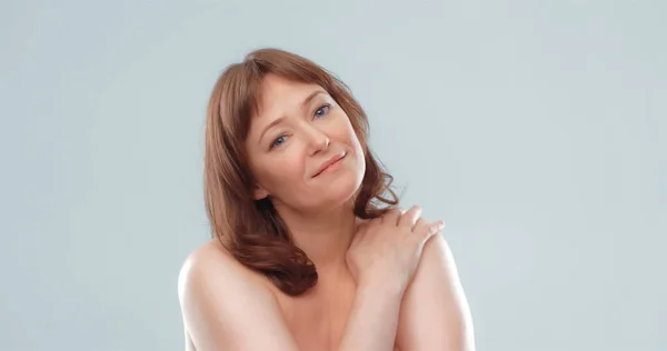 Sexy mature woman with naked shoulders looks at camera touching shoulder with hand. Body care concept. Blank for ad banner — Stock Photo, Image