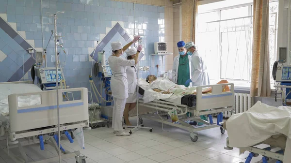 Grupo de médicos na enfermaria de ressuscitação. A equipe de médicos examina pacientes e prescreve tratamento médico. Hospital da cidade. Maio, 2020, Brovary, Ucrânia — Fotografia de Stock