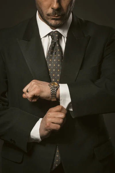 Businessman checks the time. Well-dressed white-collar worker bearded Caucasian man looks at wristwatch adjusting shirt cuffs. Close up shot. Tinted image — Stock Photo, Image