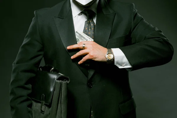 Onherkenbare zakenman verbergt of neemt geld uit zijn zak. Sluit het schot van een man met een pak biljetten van honderd dollar. Omkoping concept. Getinte afbeelding — Stockfoto