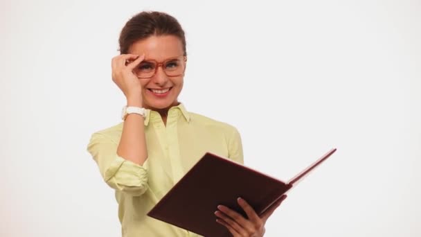 Businesswoman with brown hair smiling on camera. Freelancer in glasses standing with documents in her hands isolated on white. Prores 422 — Stock Video