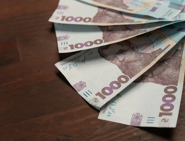 Neues ukrainisches Papiergeld im Nennwert von tausend Griwna im Halbkreis auf hölzernem Rücken mit leerem Deckel links. Selektiver Fokus im Zentrum des Bildes. Nahaufnahme — Stockfoto