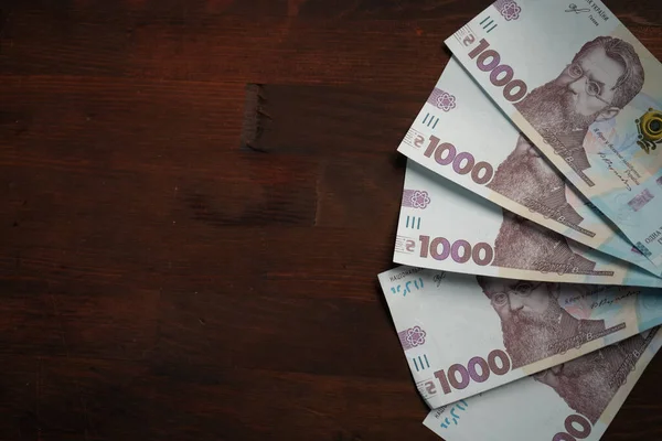 Zabawa z nowych ukraińskich banknotów nominał 1000 hrywien. Papierowe pieniądze na drewnianym tle z kopią cpace lub textspace po lewej stronie. Blisko strzału. Pojęcie bogactwa — Zdjęcie stockowe