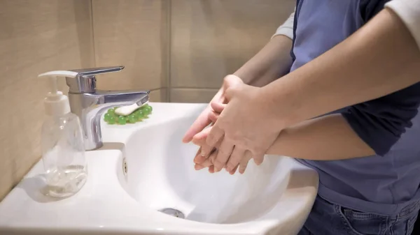Το αγόρι πλένει τα χέρια με τη μαμά. Η γυναίκα στηρίζει τα χέρια του γιου της δείχνοντας πώς να πλένει τα χέρια του καθαρά. Η έννοια της υγιεινής. Πλευρική άποψη. Κοντινό πλάνο — Φωτογραφία Αρχείου