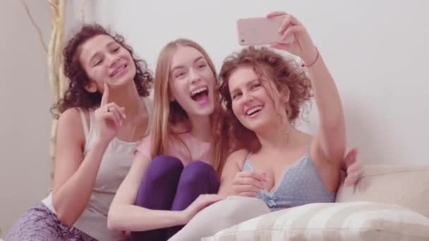 Glücklich lächelnde Mädchen machen Selfies mit dem Smartphone und nehmen Videos für soziale Medien in Heimkleidung auf. Drei attraktive Mädchen, die sich glücklich umarmen. Freizeit genießen. Prores 422 — Stockvideo