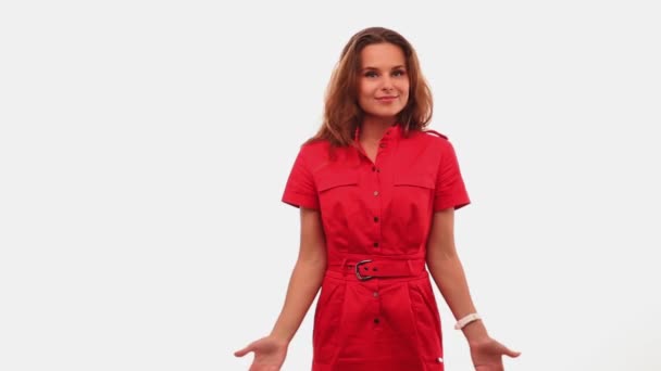 Дівчинка у червоній сукні стоїть на білому фоні, жестикулюючи невинність, піднімаючи руки веселі емоції на обличчі. Проходить 422 — стокове відео