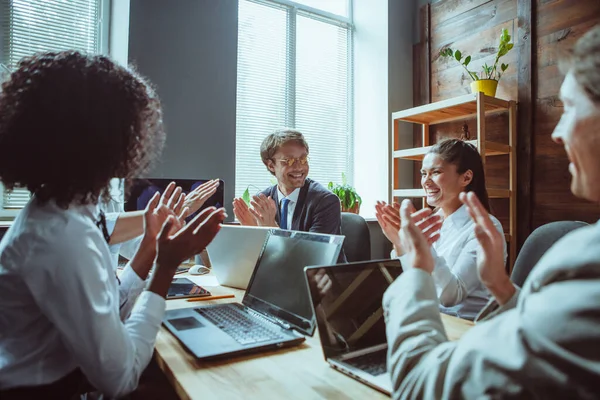 Los colegas amistosos se ríen alegremente y se aplauden. Hombres y mujeres aplauden para marcar el final del exitoso trabajo en equipo. Imagen tonificada —  Fotos de Stock