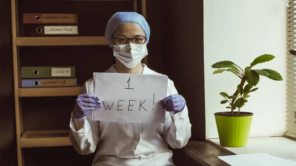 Asistentul medical demonstrează sloganul O săptămână. Femeia în uniformă medicală are un semn de numărătoare inversă. Conceptul de sănătate și medicină. Imagine colorată — Fotografie, imagine de stoc