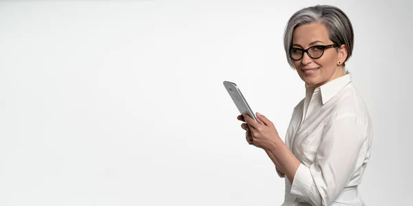 Femme d'affaires joyeuse travaille sur tablette numérique sur fond blanc. Femme mûre en blanc regardant la caméra. Blanc horizontal avec spase vide pour le texte sur le côté gauche. Concept d'entreprise ou d'éducation — Photo