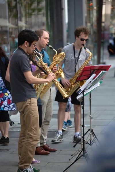 Quartetto di musicisti di strada in una strada della città. Quattro persone con strumenti a fiato, tre sassofoni e un clarinetto suonano all'aria aperta. Aprile 2013. Vienna, Austria — Foto Stock