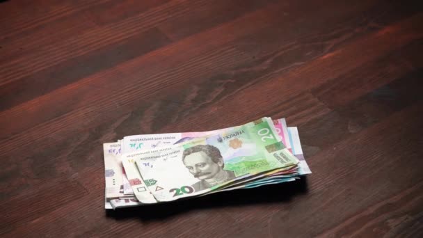 Egy köteg új ukrán pénz a fa asztalon. Papír hrivnya különböző névérték húsz hrivnya tetején. Életbér-koncepció. Családi költségvetés. Gyümölcsfélék — Stock videók