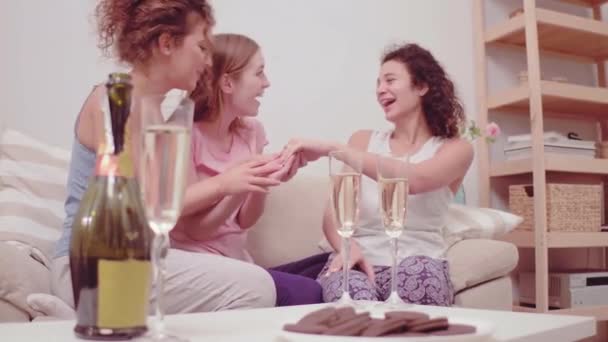 Tânăra îşi arată inelul de logodnă. Fetele se distrează împreună cu multă şampanie. Trei fete tinere fac o petrecere în pijamale. Bucurați-vă de șampanie și cookie-uri. Prores 422 — Videoclip de stoc