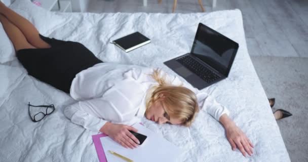 Top view fáradt szabadúszó nő alszik öltözött ágyban dokumentumok és laptop után egy hosszú, nehéz nap. Szabadúszó nő pihen az ágyban egy hosszú repülés után. Üzleti koncepció. Gyümölcsfélék — Stock videók